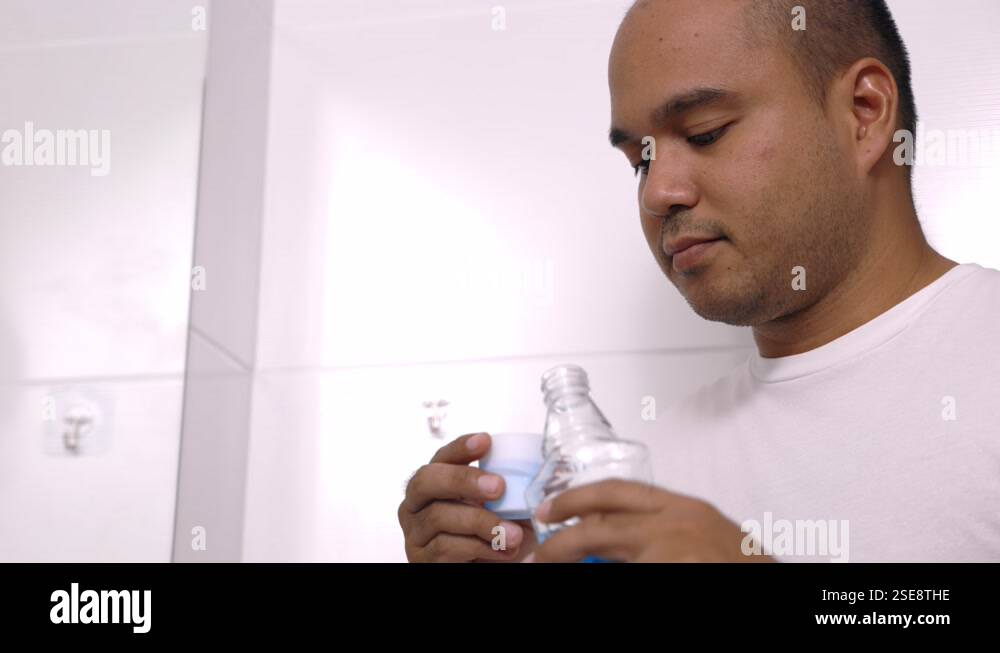 Young Man Is Gargling With A Blue Mouthwash For Good Dental Health And young-man-is-gargling-with-a-blue-mouthwash-for-good-dental-health-and