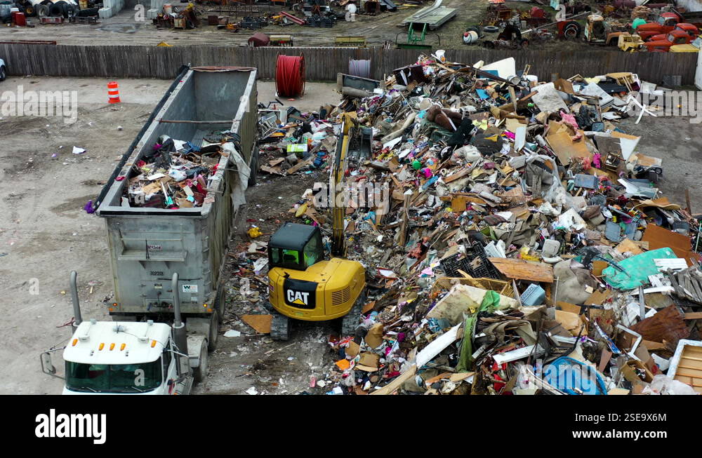 Excavator taking trash form garbage pile and throwing into trailer of ...