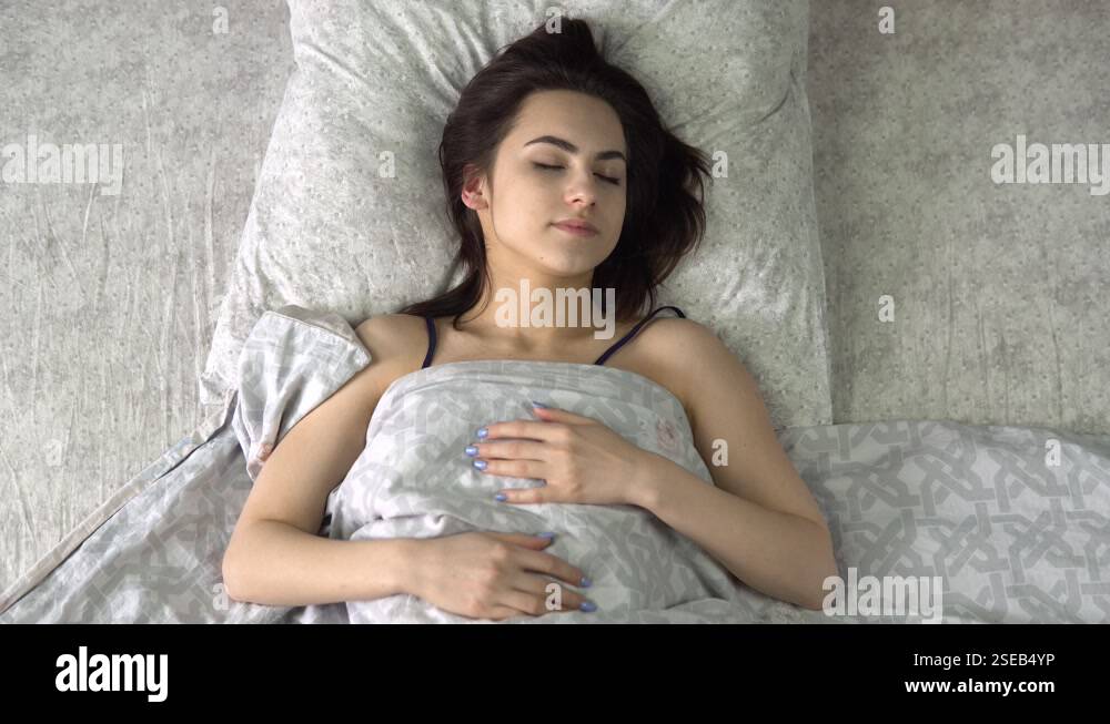 A young woman is sleeping under the covers. A girl lies in bed in his ...