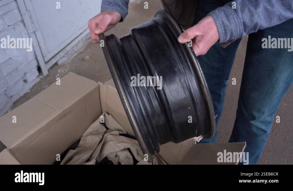 Opened cardboard delivery box and old used steel wheel rims bought ...