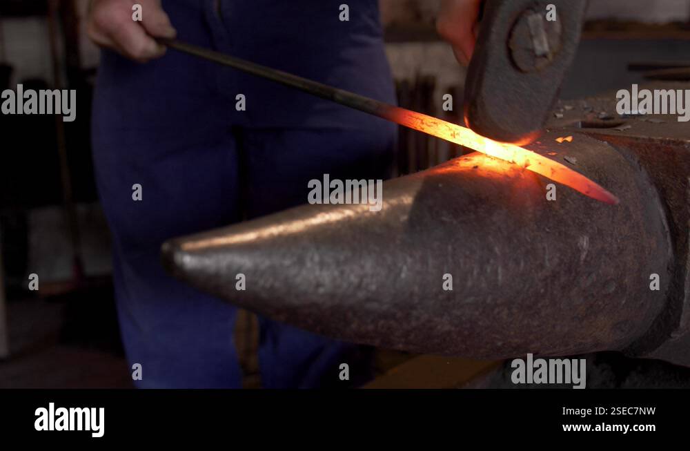 A smith forging a hot iron or steel bar on an anvil with sparks Stock ...