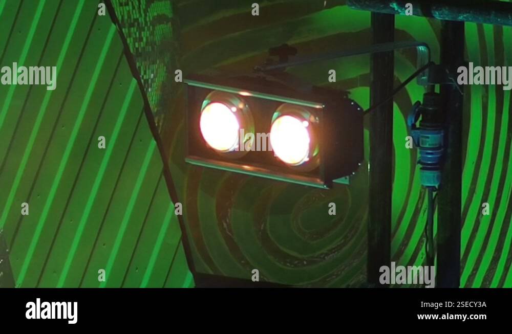 Two stage lights are blinking against a green stage background in a ...