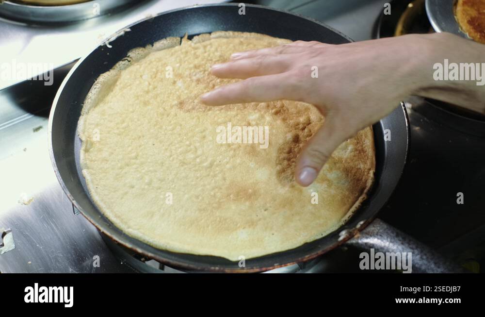 Woman turning crepe on a pan with her hand up close in slow motion. 4K ...