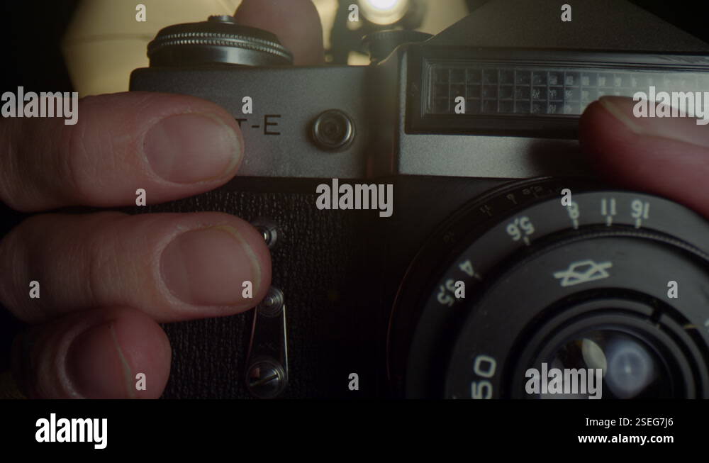 Hands of a male photographer reload a film in an old mechanical camera ...