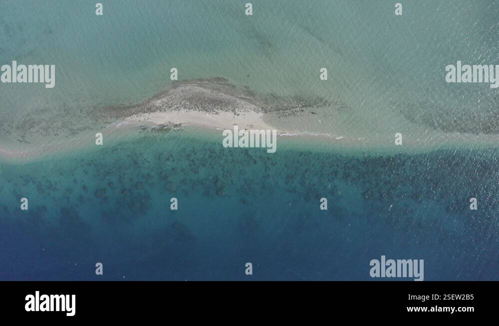 Sandy Islets Rising vertical aerial of small remote sandy islet, coral reef lagoon ...