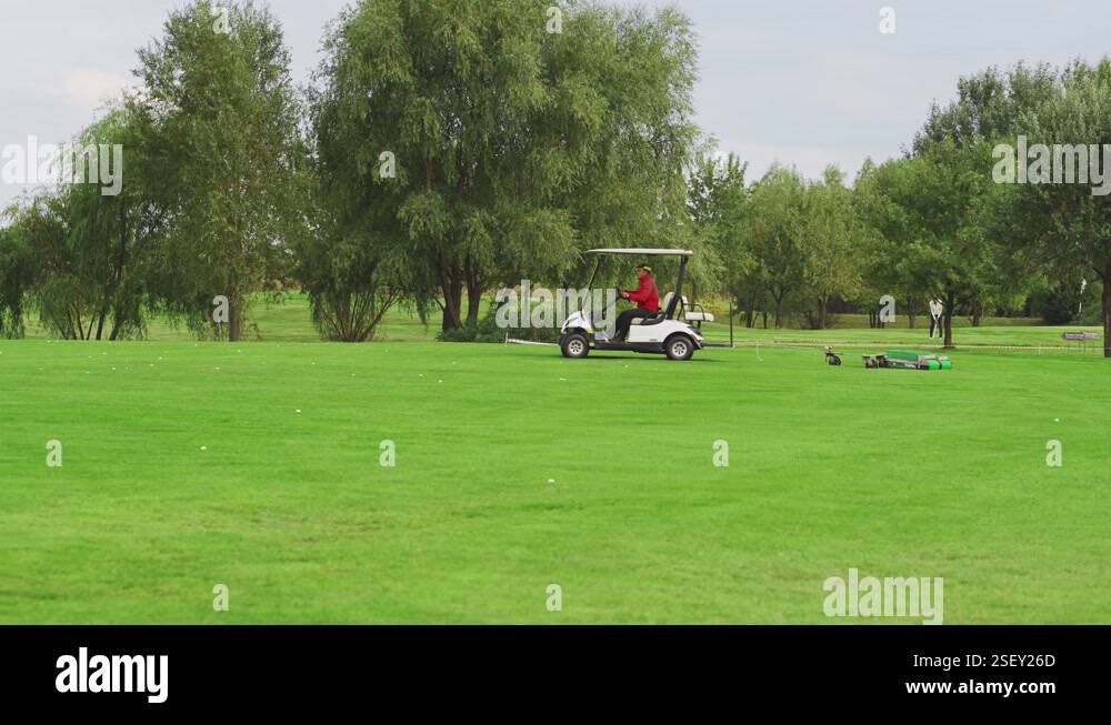 an electric car with a trailer for collecting balls rides on the golf ...