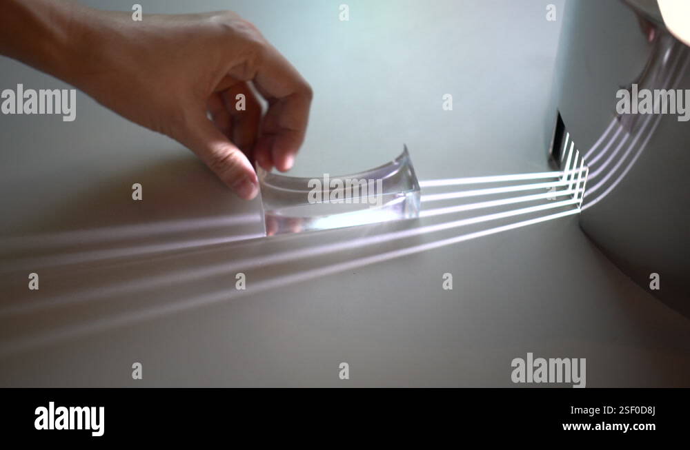 Hand moving transparent prism showing light distortion to create ...