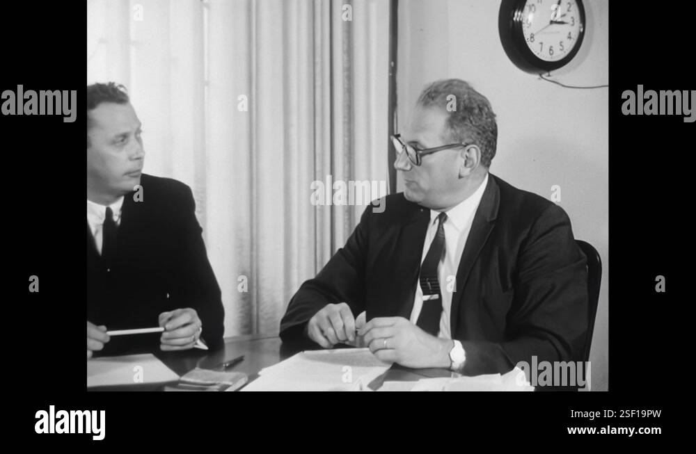1960s: Dr. Cecil Thomas speaking to interviewer. Men sitting around a ...