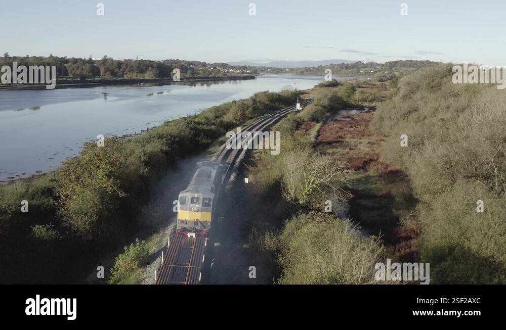 Tracking river aerial follows diesel freight train hauling steel rails ...