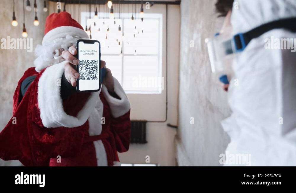 Santa Claus in red costume shows QR code before visiting the Christmas ...