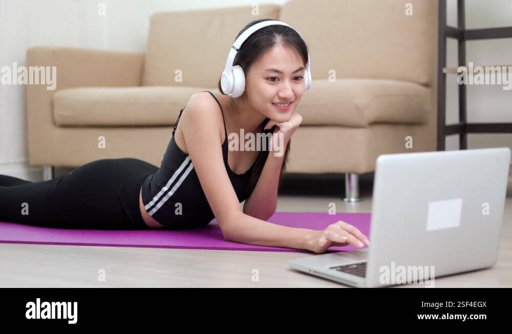 Young asian sport woman lay down on the yoga mat looking yoga lesson on ...