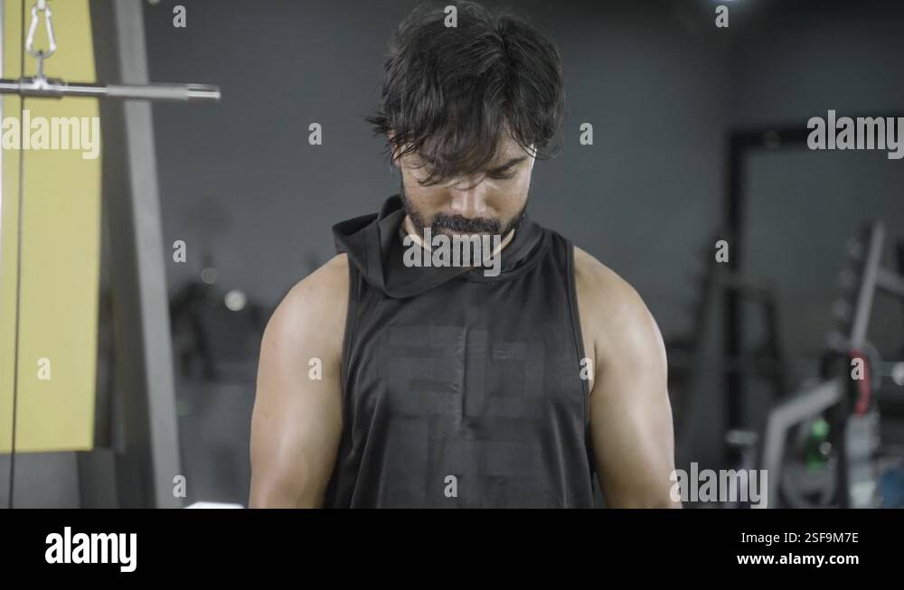 Young Indian bodybuilder busy doing biceps workout by lifting weight ...