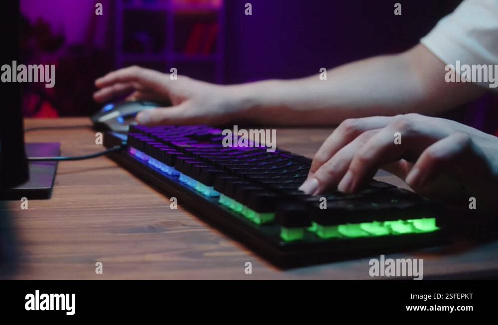 Gamer typing on backlight keyboard close-up, man playing video game ...
