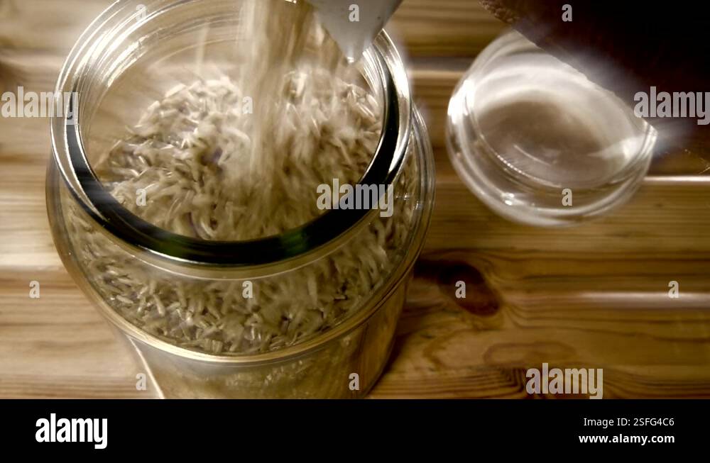 Pouring brown basmati rice from a packet into a storage jar Stock Video ...
