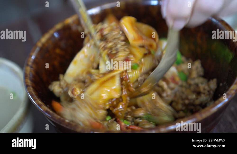 Mixing dry Chinese thick rice noodle with chilli and spicy red oil ...