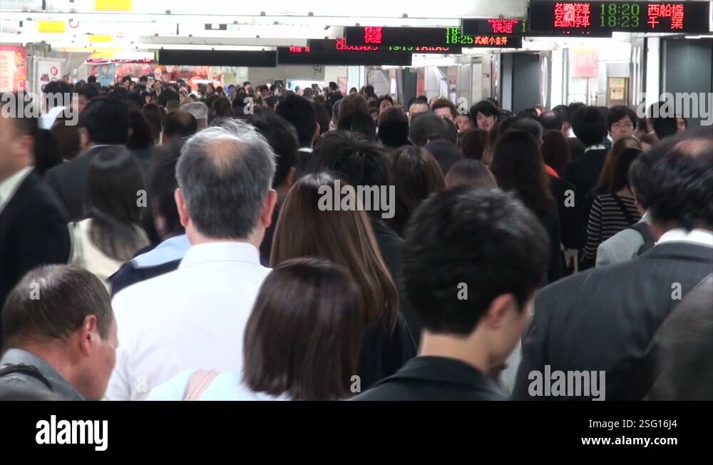 Commuting passengers walk through busy train station at rush hour in ...