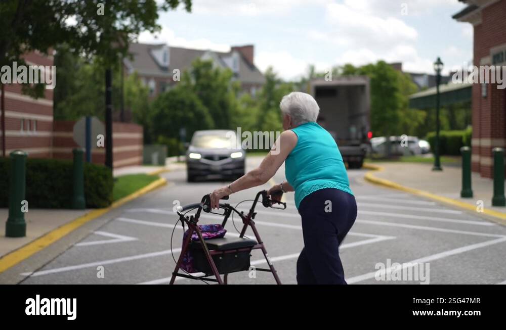 Elderly senior woman pushing a walker at pedestrian crossing with stop ...