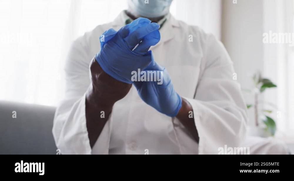 Mid section of male african american doctor wearing surgical gloves at ...