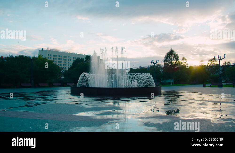 Jets of water rise up in the fountain in the evening summer city with ...
