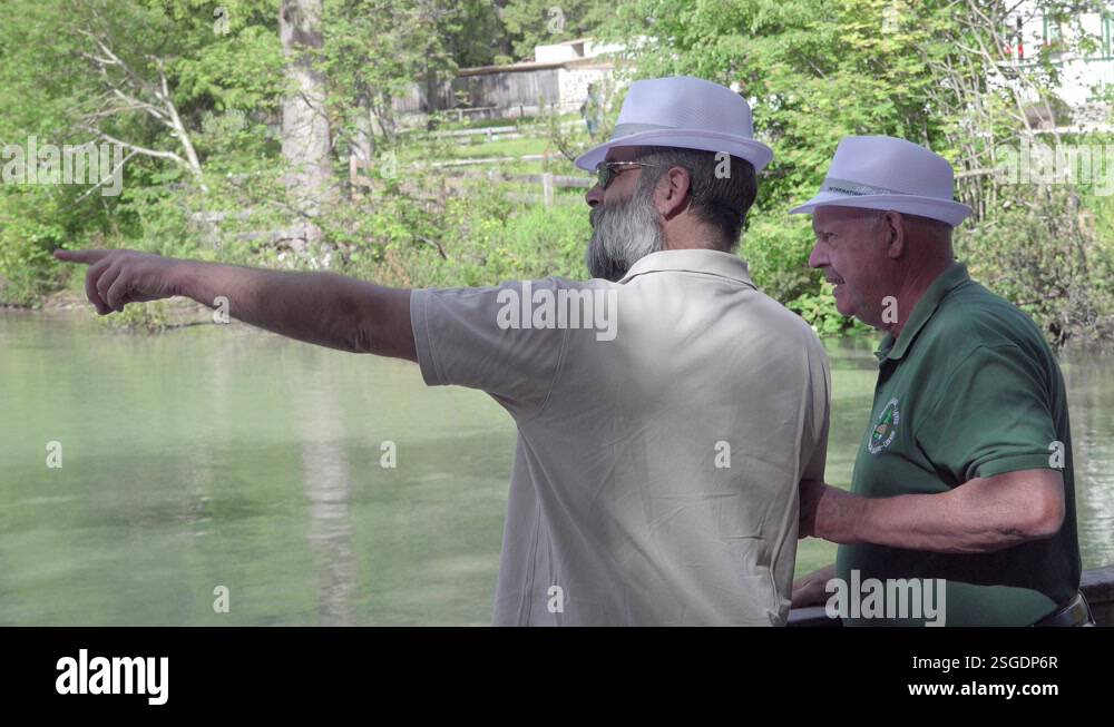 Two men wearing white hats pointing and looking at something in the ...