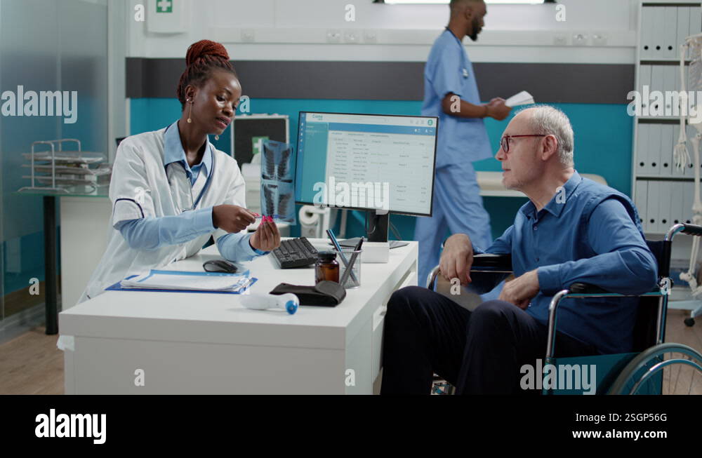 Woman medic showing x ray scan results to patient in wheelchair Stock ...