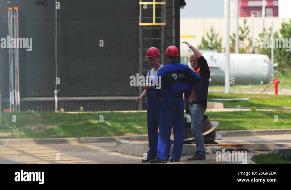 Taskmaster talks to builders near large plant building Stock Video ...