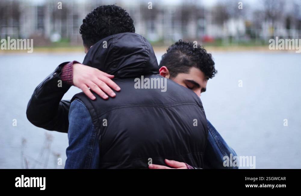 Two young middle eastern men hugging each other and saying goodbye ...