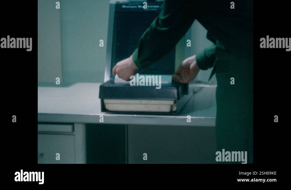 1960s: Woman removes paper copy from microfiche machine on table. Woman ...