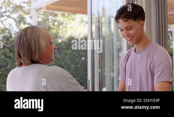 Smiling young man engaging in conversation with senior woman in bright ...