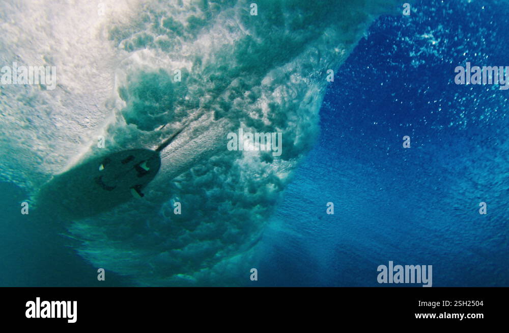 Underwater view of the breaking ocean wave with surfer riding the wave ...
