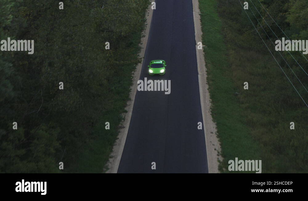 Aerial, green super race car McLaren driving on a paved asphalt road in ...