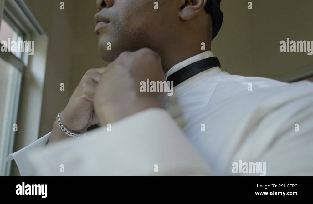 Image showcasing Groom tying bow tie. Groom getting ready on his wedding day. Shot in 4K ...