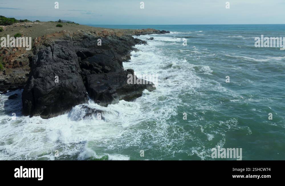 Aerial slow motion view of waves breaking against rocks on a rocky ...