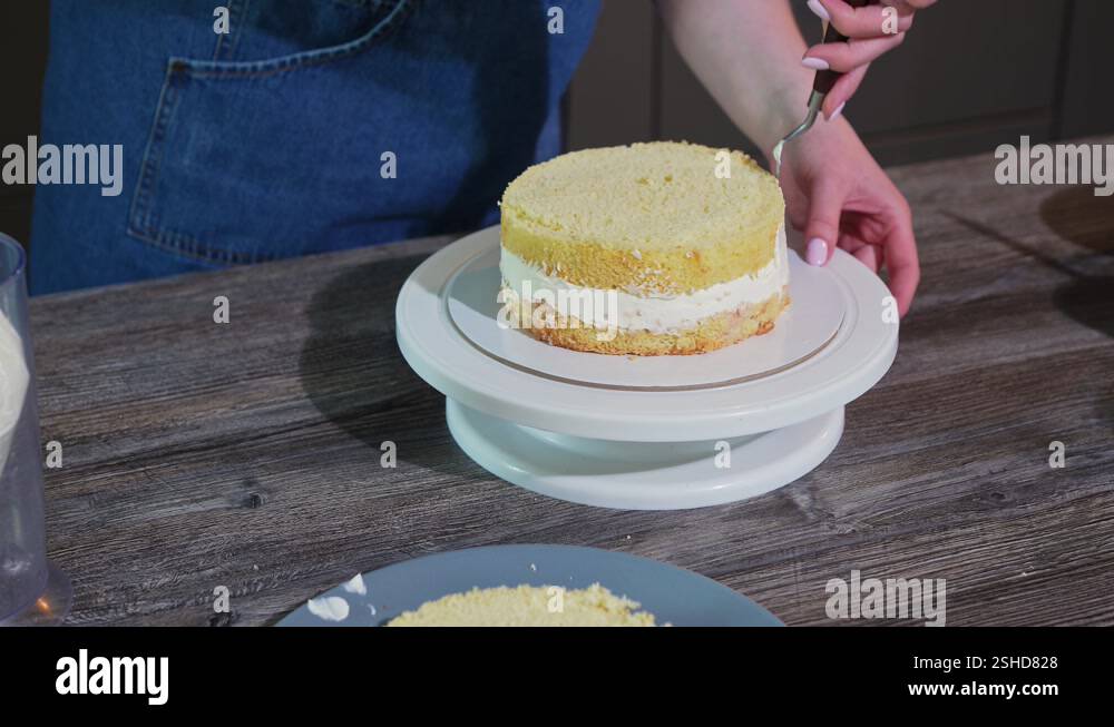Sprade Round female hands spread the layers of a round cake with curd cream using a ...