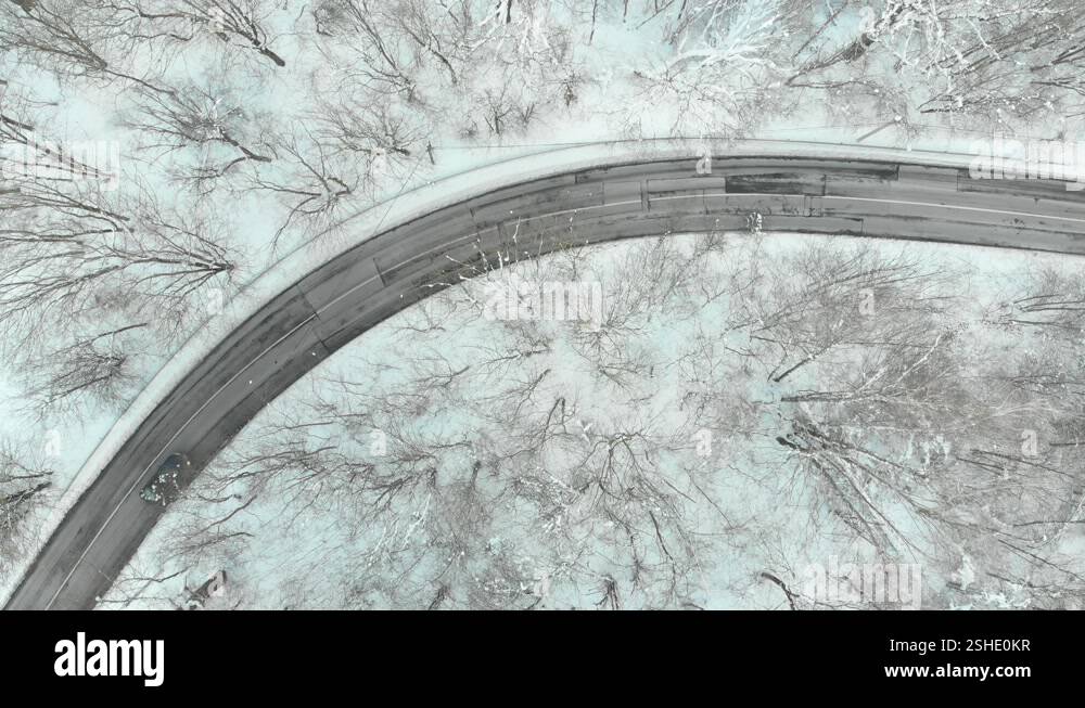 Aerial top-down view of snow covered pine forest and a road winding ...