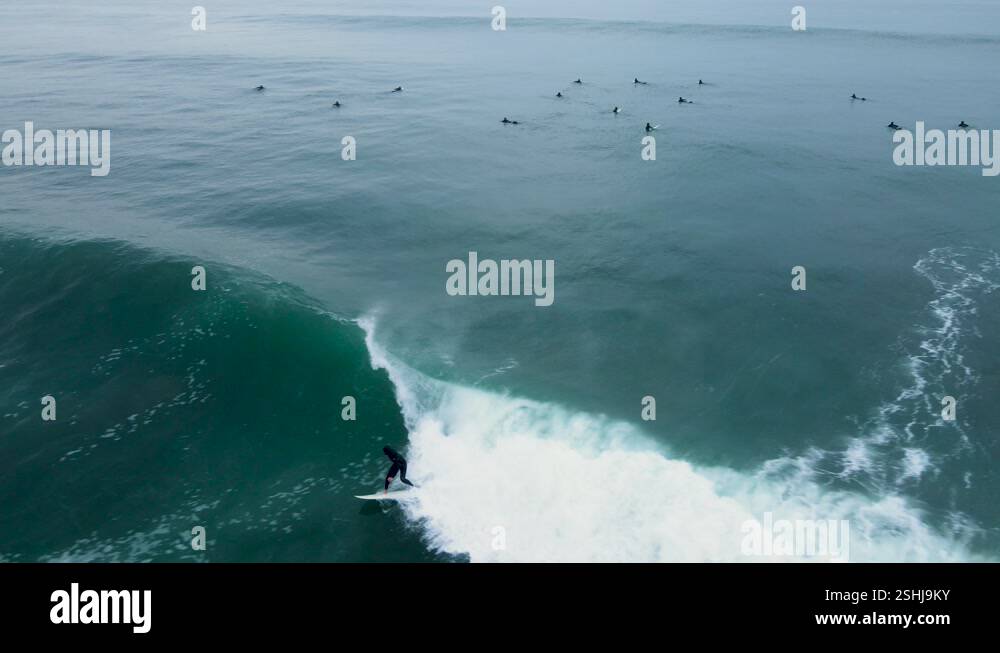 Aerial view of an unrecognizable surfer dropping into a barreling wave ...
