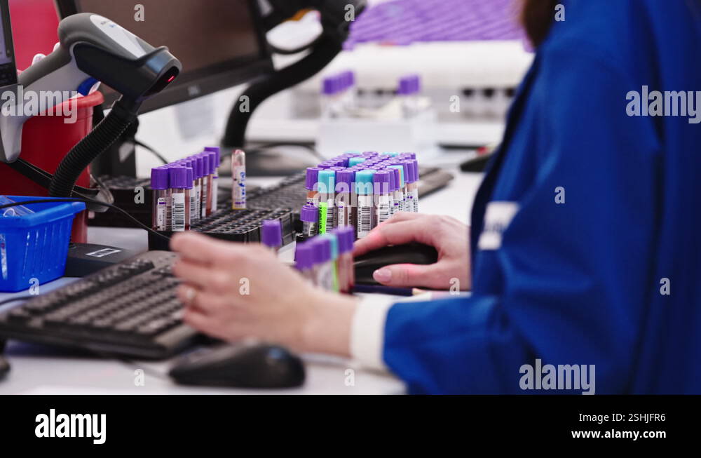 Scientist checking information on a computer with samples standing on a ...