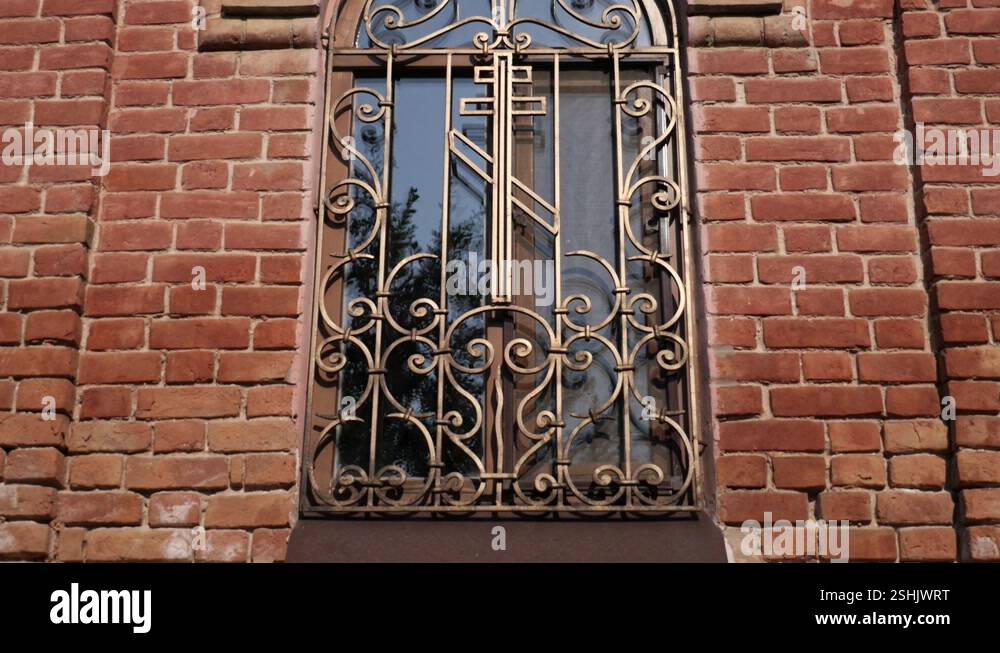 Glass window with cross and metal grating on the window. The Orthodox ...
