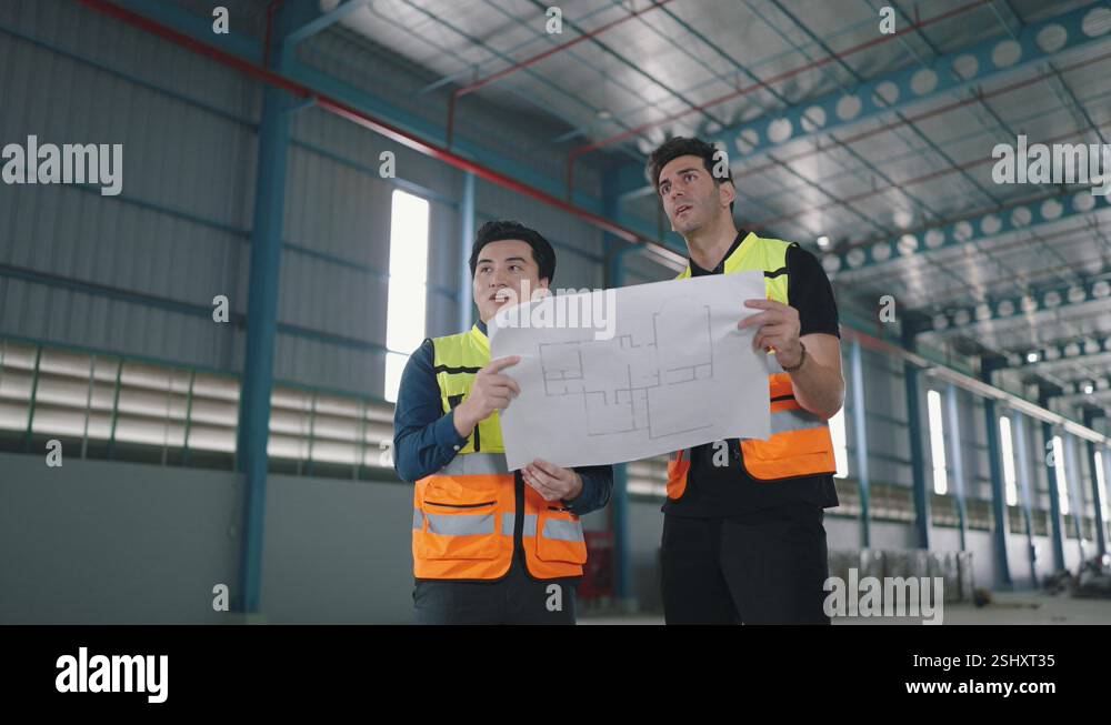 Two engineer male talking, discuss looking at paper work in factory ...