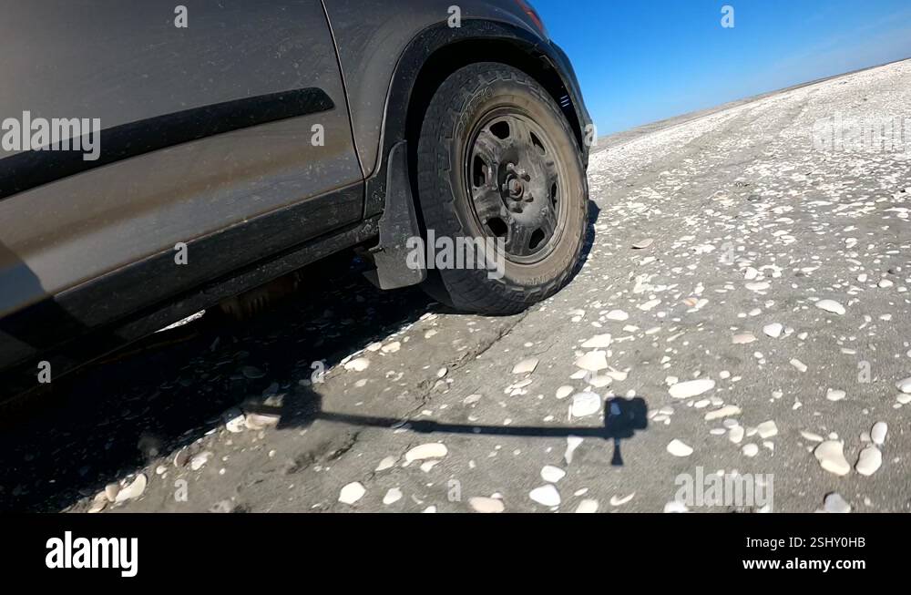 Low view of SUV racing across beach and sandy road with blue sky Stock ...