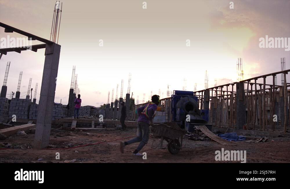african construction worker pushing sand filled wheelbarrow to concrete ...
