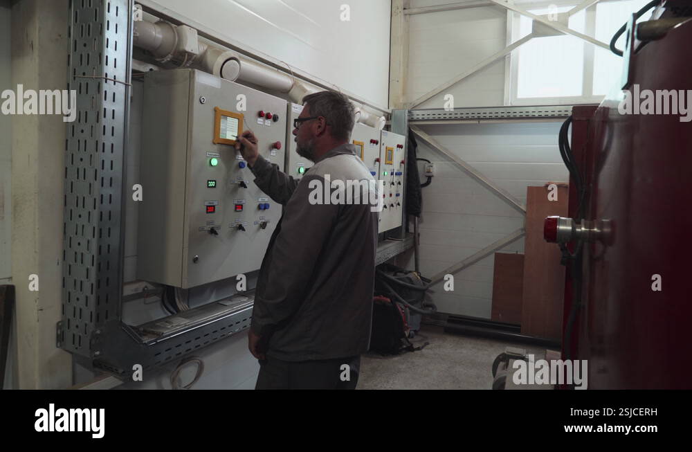 A worker is pressing the buttons on the modern industrial machine ...