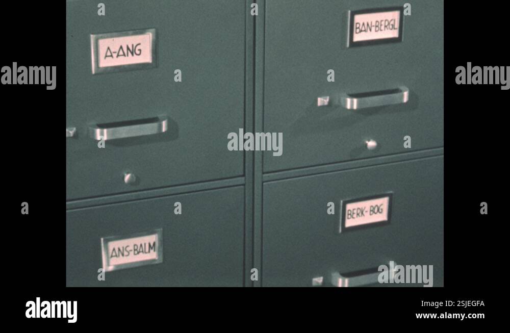 1960s: Finger traces down and flips open card filing system on tray ...