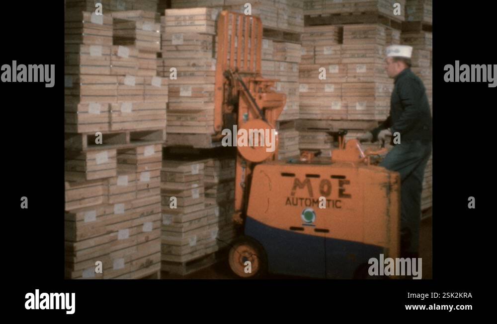 1960s: Forklift stacking cheese molds on pallet, man adjusts pallet