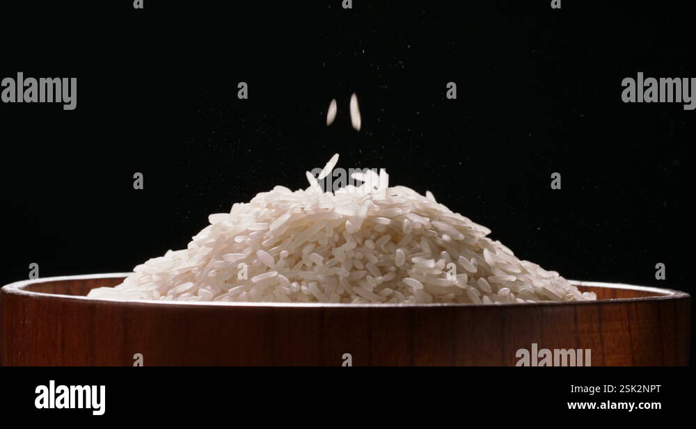 Rice fall into raw wooden bowl side view black background Close Up of a ...