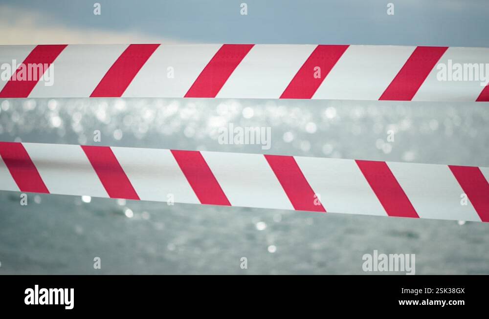 Barrien Ribon Red white warning tape barrier ribbon swinging in the wind across ...