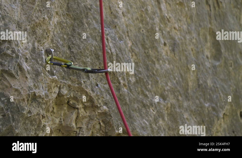 CLOSE UP, DOF: Bolt hanger with attached quickdraw and running climbing ...