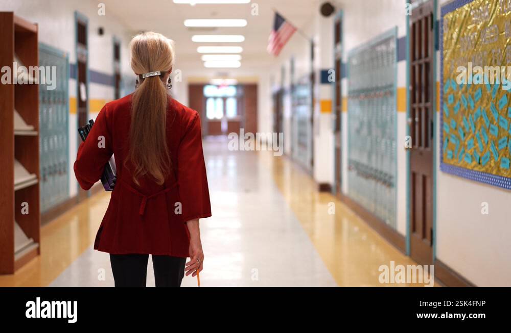 Slow motion rear view of teacher walking down an empty school hallway ...