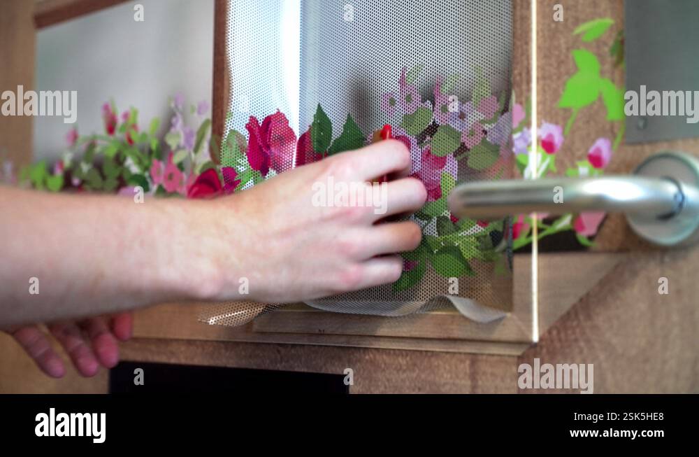 Close of vinyl sticker installer tradesman using squeegee tool to tuck ...