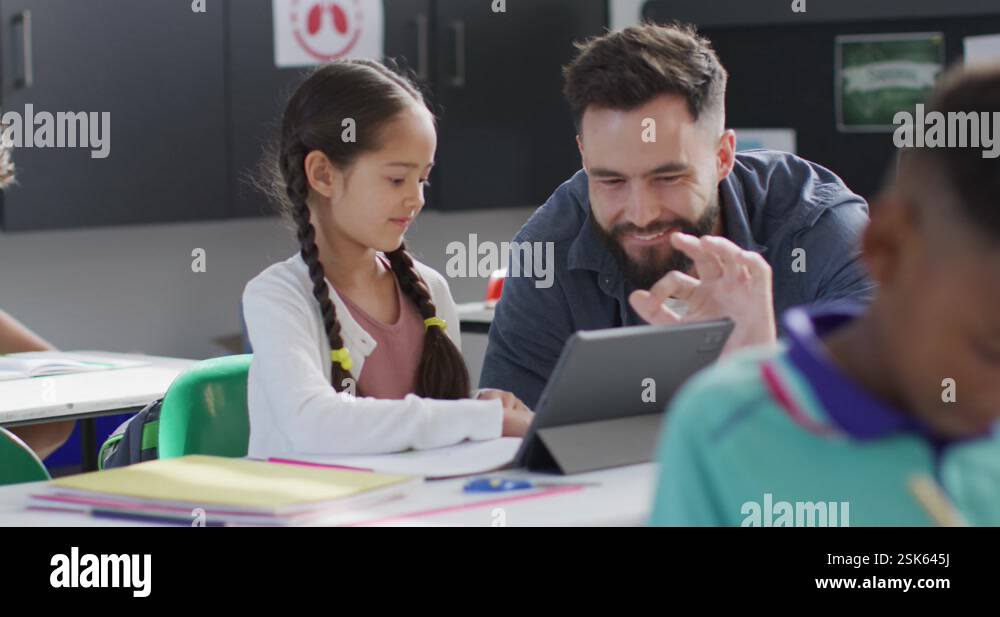 Diverse male teacher and happy schoolchildren using tablet in school ...